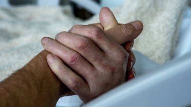 Elleri hastane yatağında başparmaklarıyla kavramış.