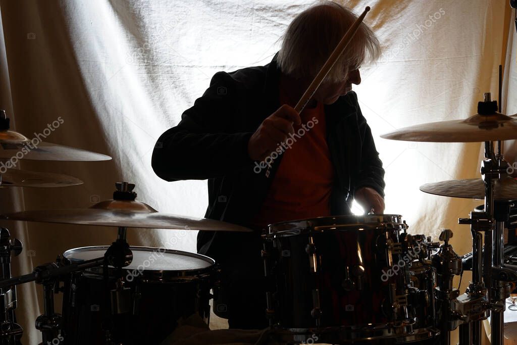 man playing an acoustic drum kit at the time of giving a cymbal