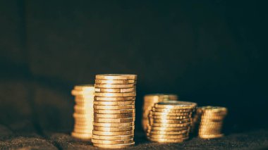 Siyah arkaplana dikey olarak yerleştirilmiş farklı boyutlarda sikkeler