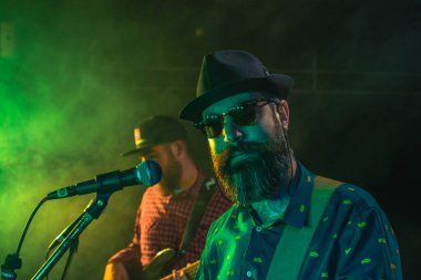 İki sakallı adam elektrikli gitar çalıyor.