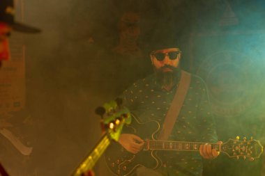 İki sakallı adam elektrikli gitar çalıyor.