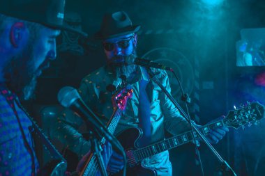 İki sakallı adam elektrikli gitar çalıyor.