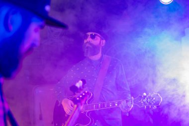 İki sakallı adam elektrikli gitar çalıyor.
