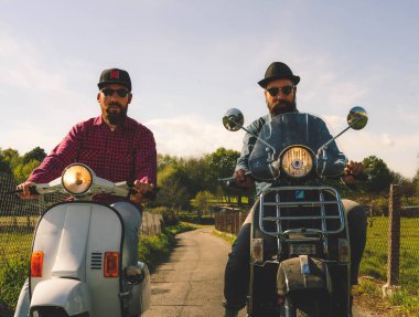 İki sakallı adam motosiklet sürüyor.