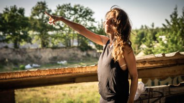 Kadın kameraya bakar ve koluyla ışığı gösterir.