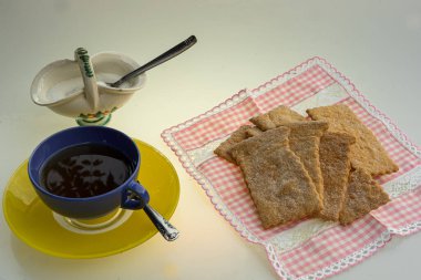 Küçük bir masa örtüsüne konmuş makarna ve şekerli bir kabın içinde eritilmiş.