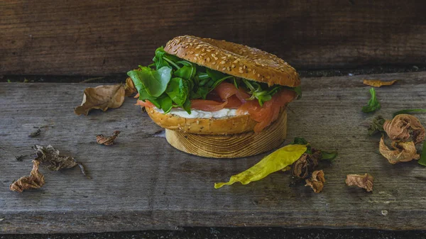 smoked salmon sandwich that also contains cream cheese and lettuce on a seed bread