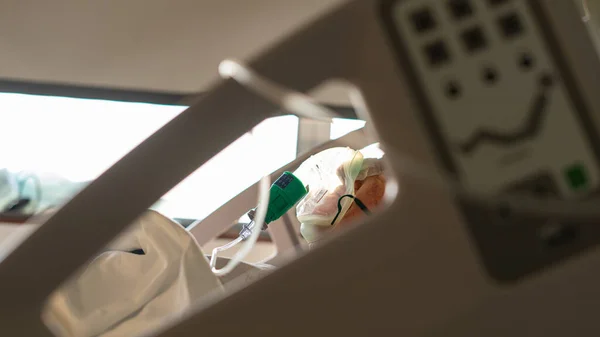 person in a hospital bed with a breathing oxygen mask
