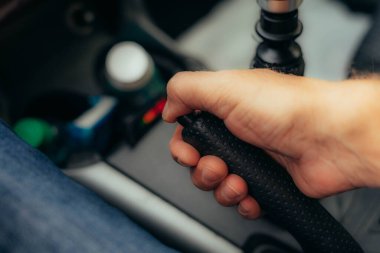 hand actuates the handbrake lever in a car