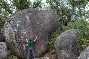 İnsan büyük oranda erozyonla çevrelenmiş bir taşı kaplamaya çalışır.