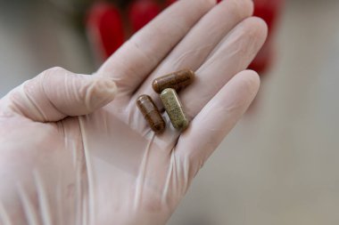 Kapsüllerde kullanışlı takviyeler. Diyet takviyeli jelatin kapsüller beyaz eldivenli erkeklerin ellerinde.