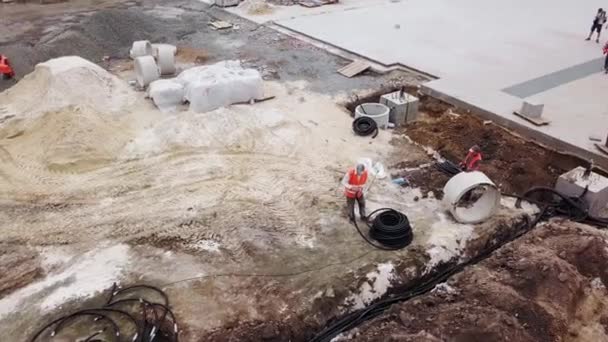 ウクライナ、マリウポリ- 2020年9月1日。フレキシブルダブルコート段ボールパイプに地下の電源ケーブルを敷設電気技師の空中。トレンチ内のパイプを介して電気ケーブルをルーティングする労働者. — ストック動画