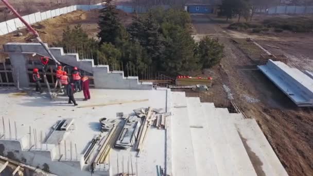 Ukraine, Mariupol - 1er septembre 2020. Aerial of concrete boom pump grue arm truck with outriggers couling building mixture into a formwork. Les travailleurs de la construction versent des murs en béton de tribune. — Video