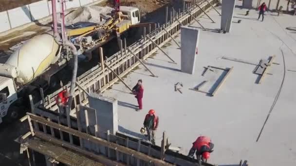 Oekraïne, Mariupol - 1 september 2020. Luchtfoto van betonnen giekpomp kraanarm truck met steunpoten gieten bouwmengsel in een bekisting. Bouwvakkers gieten betonnen muren van tribune podium. — Stockvideo