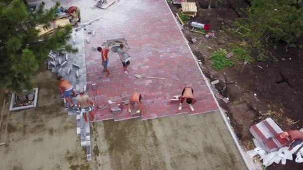 Украина, Мариуполь - 1 сентября 2020 года. Строители кладут каменные плиты на новую городскую площадь. Строители ремонтируют тротуар укладка плитки с лопатой, молоток, чтобы сделать ровную плоскую поверхность. — стоковое видео