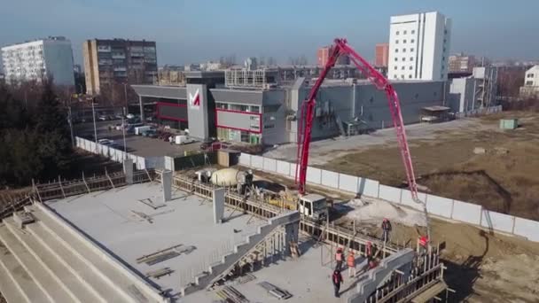 Ukraina, Mariupol - 1 września 2020 r. Antena betonowej pompy wysięgnikowej dźwigu ramię ciężarówki z wysięgnikami wylewanie mieszaniny budynku do deskowania. Robotnicy budowlani wylewają betonowe ściany trybuny. — Wideo stockowe