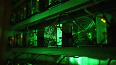 Bitcoin madencileri büyük çiftlikte. Kürsüdeki ASIC madencilik ekipmanları çelik konteynırdaki kripto para birimini rafa kaldırıyor. Engelleme teknolojisi. Güç kaynağı vantilatörleri ve ızgaralar. Sunucu odası ışıkları.