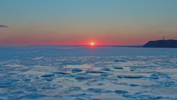 Вид с воздуха на закат над замерзшим зимним морем. Беспилотник летит вперед к рассвету и горизонту. Полет вертолёта над тающим льдом дрейфует к солнцу. Весеннее. Яркое красочное небо. — стоковое видео
