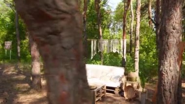 Loş kanepeli fotoğraf odası ve çam ormanlarındaki açık hava düğün mekanında boho stili kargo paletleri masası. Bohem dekor.