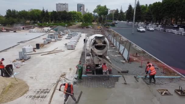 Oekraïne, Mariupol - 1 september 2020. Luchtfoto van cement mixer truck gieten kant-en-klare bouwmengsel voor beton dekvloer van nieuwe stadsplein op bouwplaats. Werknemers dekvloer egaal oppervlak. — Stockvideo