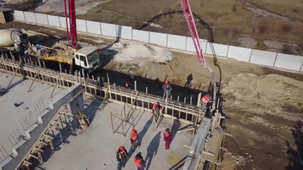 Ukraine, Mariupol - 1. September 2020. Antenne eines Betonauslegerpumpenkranwagens mit Stützen, die das Baugemisch in eine Schalung gießen. Bauarbeiter gießen Betonwände der Tribünenbühne. — Stockvideo