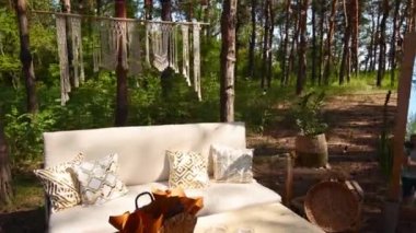 Loş kanepeli fotoğraf odası ve çam ormanlarındaki açık hava düğün mekanında boho stili kargo paletleri masası. Bohem dekor.