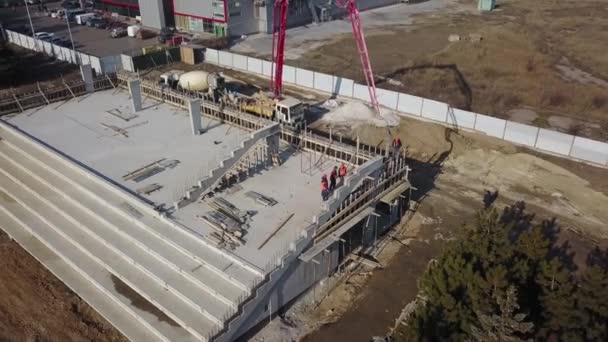 ウクライナ、マリウポリ- 2020年9月1日。Aerial of concrete boom pump crane arm truck with outriggers pouring building mixture into a formwork.建設労働者はトライブリーンステージのコンクリート壁を注ぐ. — ストック動画