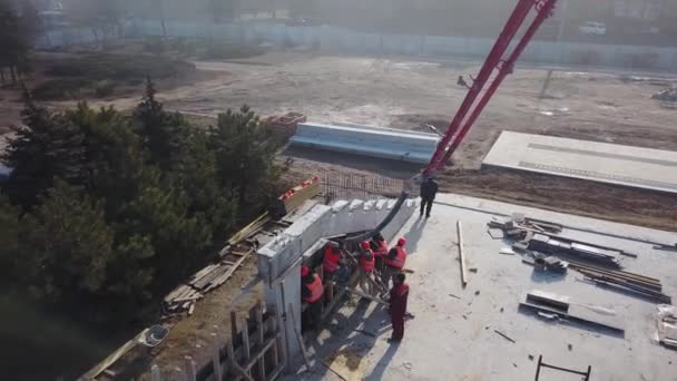 Украина, Мариуполь - 1 сентября 2020 года. Воздушный кран для подъема бетонного насоса с детонаторами, заливающими строительную смесь в опалубку. Строители заливают бетонные стены трибуны сцены. — стоковое видео
