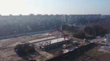 Beton patlayıcı vinç kol kamyonu havadan geliyor. Formalitelere bina karışımı dökülüyor. İnşaat işçileri tribün sahnesinden beton duvarlar dökerler. Yukarıdan görüntüle.