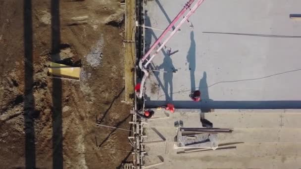 Oekraïne, Mariupol - 1 september 2020. Luchtfoto van betonnen giekpomp kraanarm truck met steunpoten gieten bouwmengsel in een bekisting. Bouwvakkers gieten betonnen muren van tribune podium. — Stockvideo