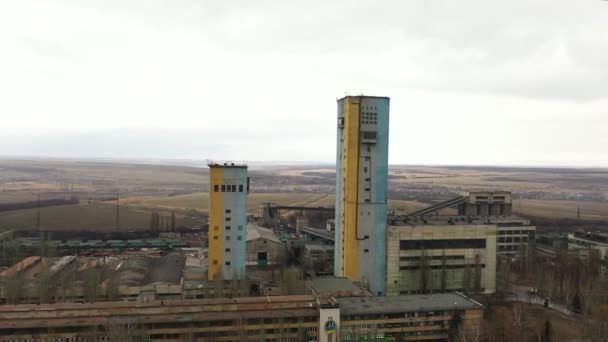 Old coal mine elevator and slag heaps on a cloudy day. Vintage coal mining shaft building, weathered factory and constructions. Fossil fuel and minerals mining heavy industry landscape with terrikons. — 图库视频影像