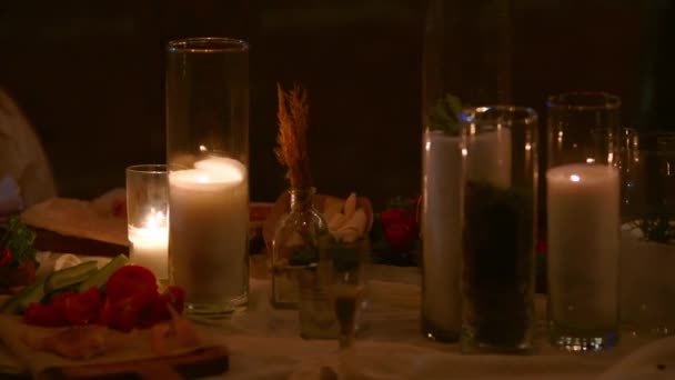 Bruiloft feest banket buiten in het bos. Eettafel ingericht in boho stijl met brandende kaarsen, witte doek, bloemen, geserveerd met borden, servies, borden, maaltijden, servies en drankjes 's nachts. — Stockvideo