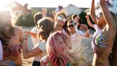 Neşeli kız Holi festivalini renkli tozlara bulanmış arkadaşlarıyla kutluyor. İnsanlar Hindu bayramında eğleniyor. Erkekler dans eder, yavaş çekimde kumsala atlarlar. Covid salgın izolasyonunun sonu