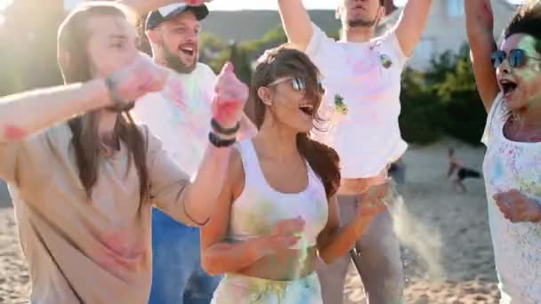 Las personas alegres se divierten salpicando polvo de colores, celebran el festival Holi en cámara lenta. Los amigos juegan con colores secos en el festival hindú de primavera, colores, amor. Fin del aislamiento pandémico covid — Vídeo de stock