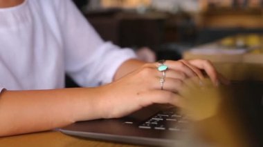 Kafedeki dizüstü bilgisayarlı klavyede daktilo kullanan kadın serbest çalışanların elinde kameralar kayıyor. Ofiste internetle çalışan bir iş kadını. Kadın internet üzerinden kahve dükkanında yeni bir iş arıyor. Yavaş çekim.