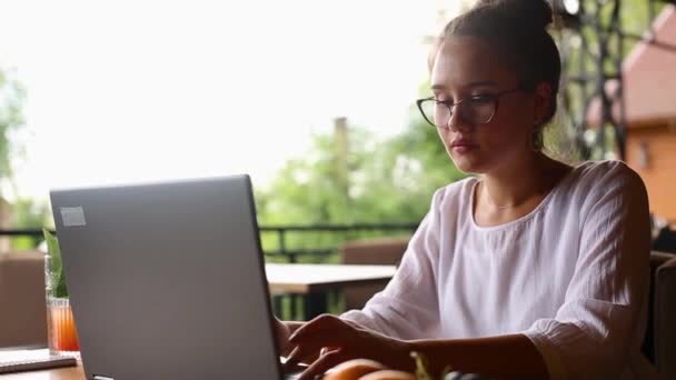 La cámara se desliza alrededor de freelancers femeninas que escriben en el teclado del ordenador portátil en cámara lenta. Empresaria mixta trabajando en la oficina. Mujer multiétnica busca nuevo trabajo en internet en la cafetería. — Vídeo de stock