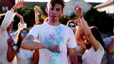Renkli toza bulanmış yakışıklı adam göğsüne yumruklar yapıştırıyor. Holi Festivali 'nde barış işareti gösteriyor. Kızlar dans eder, erkekleri yere serer, güler. Kilitlemenin sonu, covid salgın, kısıtlamalar