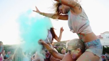 Holi festivalinde renkli pudraya bulanmış iki kadın erkek omuzlarında oturuyor. Arkadaşlar Hint bayramında eğlenir, bahar. Covid salgınının sonu, tecrit, kısıtlamalar, tecrit