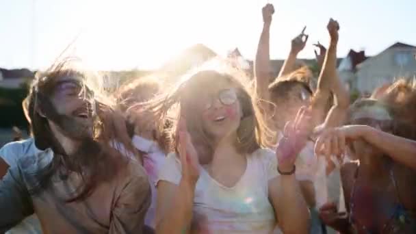 Pessoas alegres celebram o festival Holi manchado em pó colorido. Os amigos divertem-se em férias hindus de primavera, cores, amor. Os rapazes dançam, saltam na praia em câmara lenta. Fim do isolamento da pandemia vívida. — Vídeo de Stock