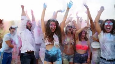 Zıplayan ve dans eden gençler Holi festivalinde yavaş çekimde havaya kuru boya atıp eğleniyorlar. Arkadaşlar Hindu tatilini kutluyor ve tecrit, covid salgın, karantina sona eriyor.