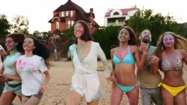 Genç insanlar kumla kaplanmış renkli tozlarla denize doğru koşuyorlar. Birbirlerini yavaş çekimde tutuyorlar. Hindu bahar tatili, birlik, aşk. Covid salgın izolasyonunun sonu. Sonraki çekim.