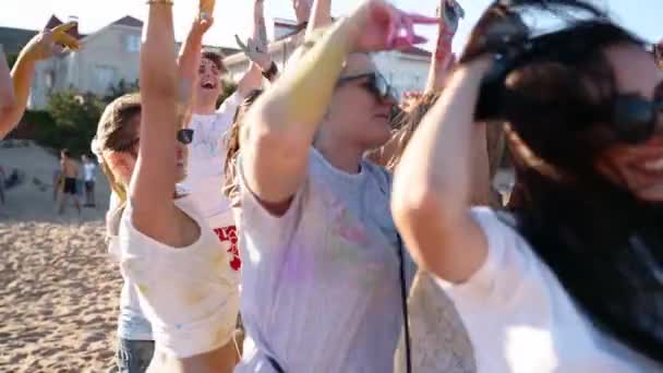 Gut gelaunte Menschen feiern Holi-Fest, das mit buntem Puder befleckt ist. Freunde haben Spaß am hinduistischen Fest des Frühlings, der Farben, der Liebe. Jungs tanzen, springen in Zeitlupe auf den Strand. Ende der Pandemie-Isolation. — Stockvideo