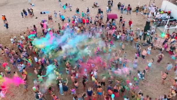 Mariupol, Ukraine - 7 juillet 2019. Aerial foule sur holi festival éclaboussant poudre colorée. Les gens jettent des couleurs sèches dans l'air debout sur le sable pour célébrer la fête de l'amour, le printemps, l'unité. — Video