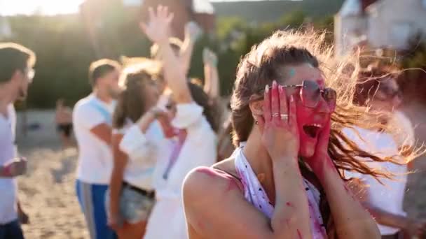 Glada kvinna stänk färgat puder på kinderna, sticker ut tungan, har kul på Holi festival i slow motion. Människor firar hindu semester och slut på coronavirus pandemi, karantän, restriktioner — Stockvideo