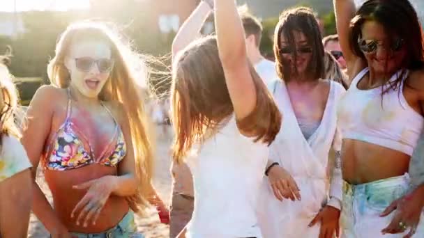 Vrolijke mensen vieren Holi festival gekleurd in poeder. Vrienden veel plezier bij hindoe vakantie van de lente, kleuren, liefde. Jongens dansen, springen op het strand in slow motion. Einde van hevige pandemische isolatie. — Stockvideo