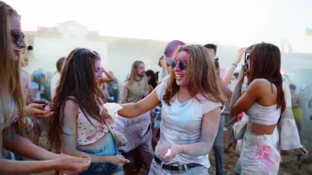 Vrolijke jonge vrouw in een zonnebril ingesmeerd in gugal poeder deelt droge kleuren met vrienden op Holi festival in slow motion. Outdoor hindoe vakantie feest. Einde van de afsluiting, hevige pandemie, beperkingen — Stockvideo