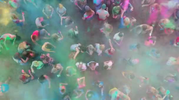 Mariupol, Ucrania - 7 de julio de 2019. Aérea - multitud en el festival holi salpicando polvo de colores. La gente arroja colores secos en el aire de pie sobre la arena para celebrar el festival del amor, la primavera, la unidad. — Vídeos de Stock