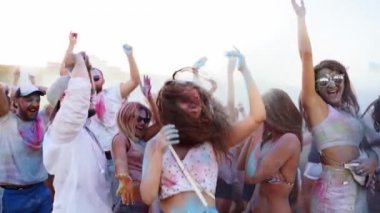Zıplayan ve dans eden gençler Holi festivalinde yavaş çekimde havaya kuru boya atıp eğleniyorlar. Arkadaşlar Hindu tatilini kutluyor ve tecrit, covid salgın, karantina sona eriyor.