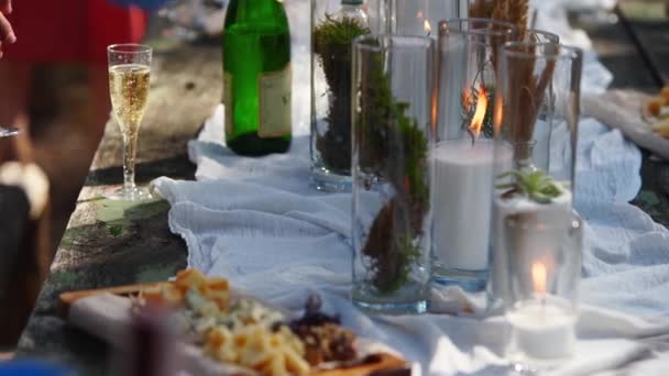 Πρόσωπο παίρνει τυρί από τραπέζι διακοσμημένο σε στυλ Boho με κεριά, ύφασμα, λουλούδια, σερβίρεται με επιτραπέζια σκεύη, πιάτα, γεύματα, ποτήρια, ποτά. Γάμο δεξίωση σε εξωτερικούς χώρους στο δάσος. — Αρχείο Βίντεο