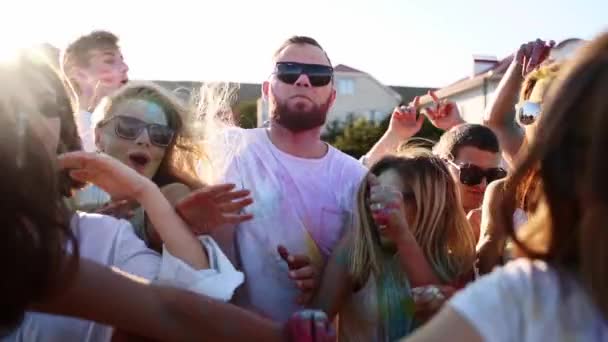 Beau homme avec un visage fort filant à travers la foule, commence à crier. Guy obtient deux poignées de poudre colorée dans la bouche par de belles filles pour s'amuser au festival Holi. Fin de l'isolement des covidés — Video